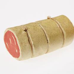 Red and white roll of meat bound with three strands of string. Miniature model.