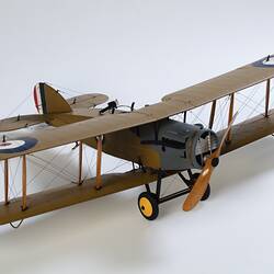 Model biplane aeroplane painted mustard brown with grey engine. Three quarter right view from above.