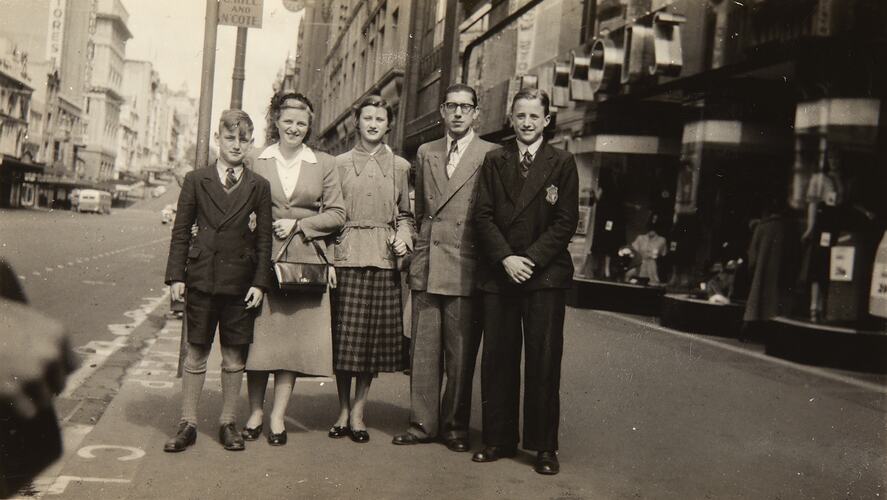 Family pose on city street. Two teenage boys and a teenage girl with their mother and father.