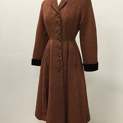 Long coat made from a reddish brown ribbed fabric.