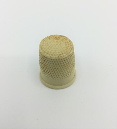 Cream plastic dimpled thimble.