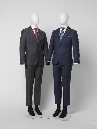 Two suits. Left suit jacket and pants has brown large check pattern. Right suit jacket and pants is blue with thin red square check pattern.
