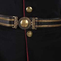 Detail of navy officer's jacket with brass buttons. Gold and navy belt.