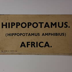 Brown rectangular label with hand painted black lettering.