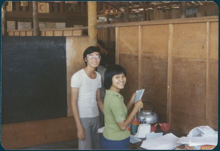 A man and woman smiling towards camera in a wooden room.