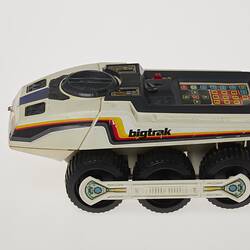 Cream six-wheeled toy truck. Stickers on sides. Left profile.