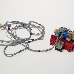 Grey cables attached to black, blue, red, yellow and grey plastic component.