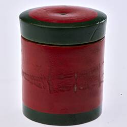 Red painted, cylindrical wooden box. Dark green trim around lid and base.