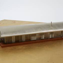 Model of a house with an arched roof, corrugated iron and wide expanses of glass.