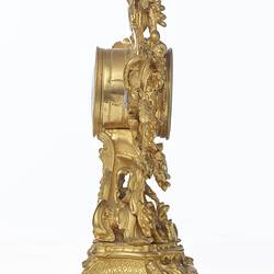 Elaborately decorated gold mantel clock. Right profile.