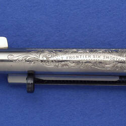 Silver Colt firearm with a decorated barrel.