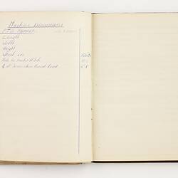 Open book with off white ruled pages. Handwritten text on left page.