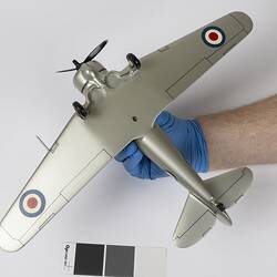 Underside of silver model aeroplane. Red, white, blue roundels on wings and body. Black propeller and wheels.
