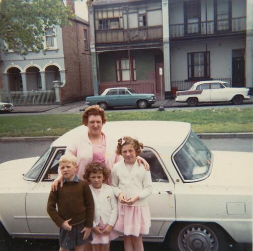 Digital Photograph - Woman, Boy & Two Girls in front of a Car & Terrace Houses, Carlton, circa 1970