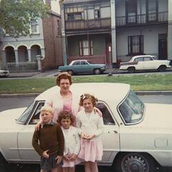 Digital Photograph - Woman, Boy & Two Girls in Front of Alfa Romeo Car & Terrace Houses, Carlton, circa 1970
