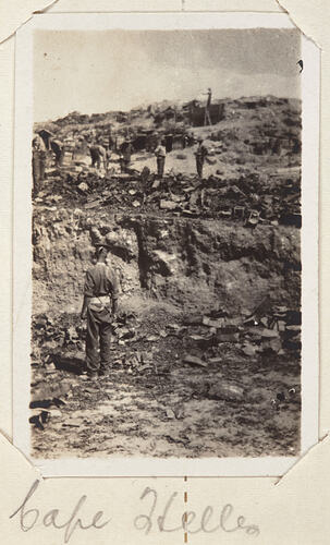 Servicemen standing among a dug up and uneven landscape.