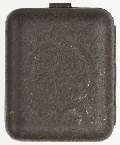 Back of dark metal decorative case with hinges along right edge.
