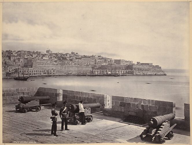 Township with fortifications, port in background. Two soldiers next to canon, third leans on it.