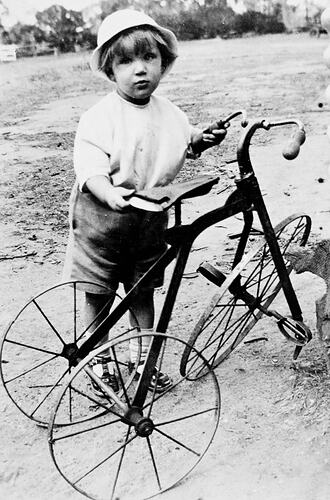 Young boy with a broken tricycle.