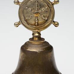 Brass bell with decoration on handle.
