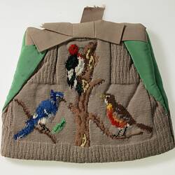 Tea cosy decorated with three birds on branches.