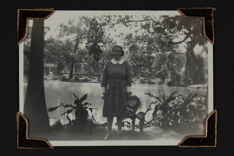 Woman in uniform standing in front a pond with trees surrounding.