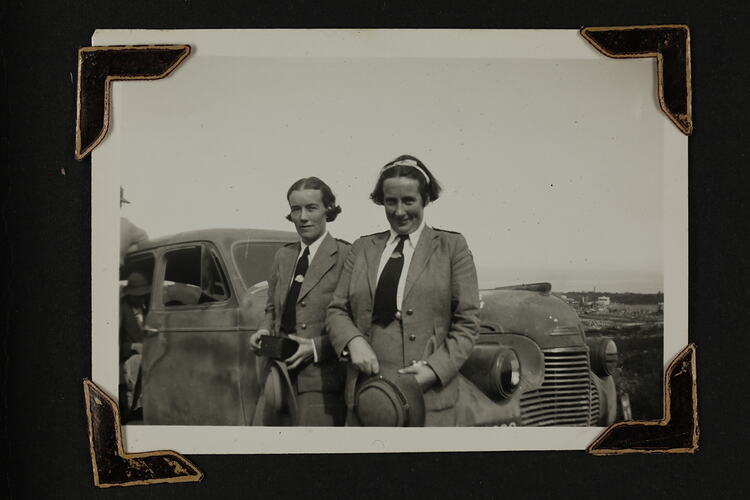 Two woman in uniform standing in front of a car.