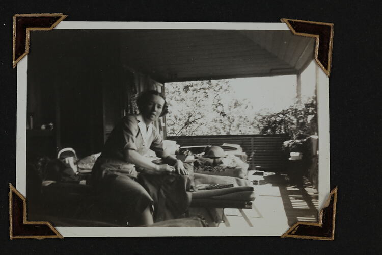 Woman sitting on military hospital stretcher, on a veranda.