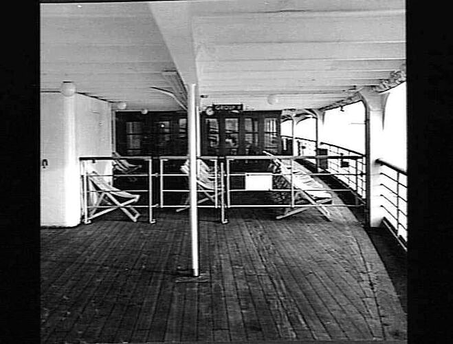 Ship exterior. Gated section with deck chairs and interior behind.