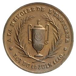 Round medal, central urn framed by wreath. Text around.