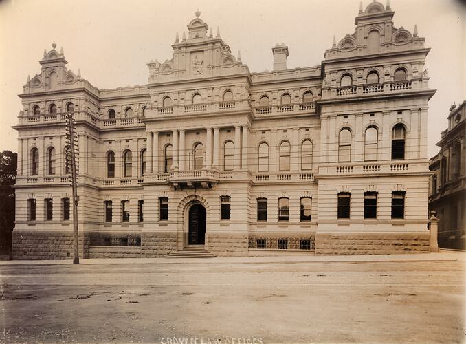Ornate three storey building with three peaked roof sections. View from across street.