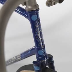 Detail of blue metal bicycle head tube with white decorative motif.