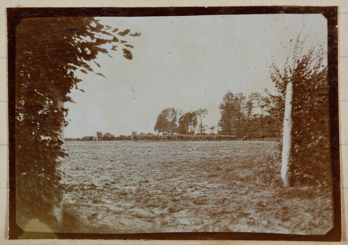 Farm field in Belgium with soldiers in distance.