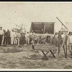 Men standing with telescopes, and tents.