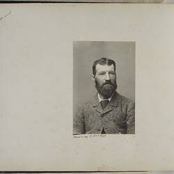 Printed photograph of bearded man wearing suit.