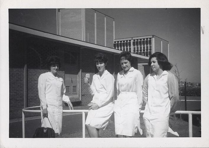 Four women outside, wearing factory uniforms.