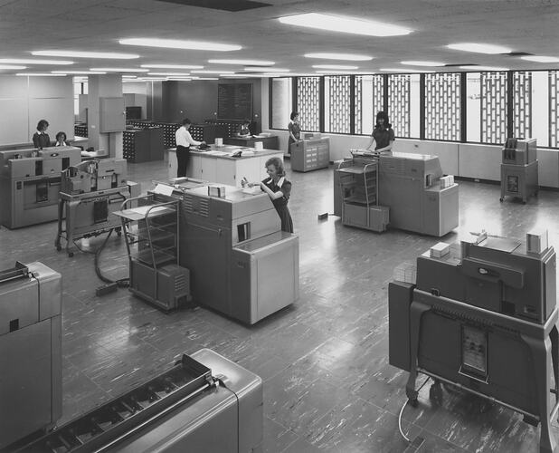 Women operating punch card machines in a well lit room.