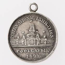Round silver coloured medal with building, text above and below. Loop at top.