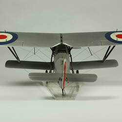 Silver model biplane model with red, white, blue rondels on wings and fuselage. Silver propeller. Back view.