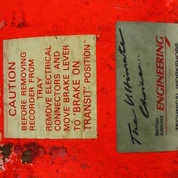 Red cylindrical container with two electrical cords at one end.