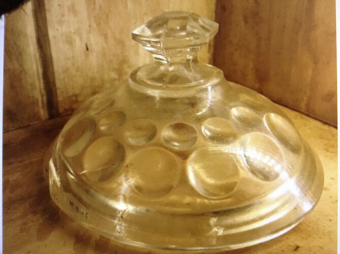 Domed glass lid with scalloped circle patterns and angular cut handle.