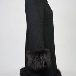 Black woollen double-breasted coat with fur collar, cuffs and hem. Right profile.