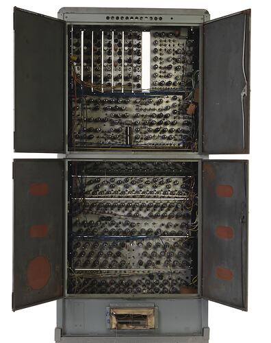 Grey metal cabinet, four open doors. Contains circuit boards, wires, valves, switches. Vent hole at base.