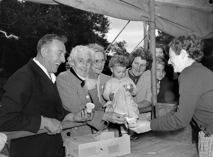 Woman serving icecream to a group of people that includes a young child.