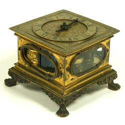 Decorative table clock, square gilded brass case on four feet.