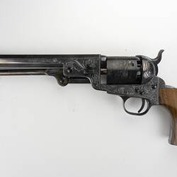 Engraved revolver with octagonal barrel and wooden handle. Left profile.