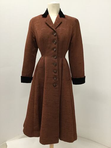 Long coat made from a reddish brown ribbed fabric.