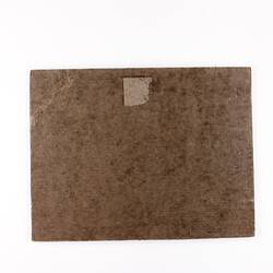 Plain back of a brown exhibition label.
