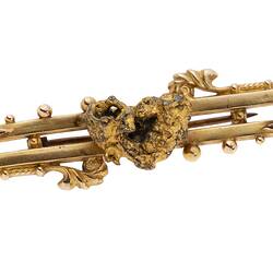 Gold double bar brooch with decorative detailing, featuring a small natural gold nugget.