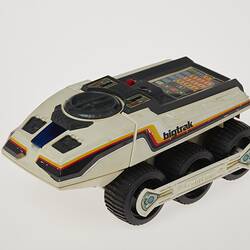 Cream six-wheeled toy truck. Stickers on sides. Left front three-quarter profile.